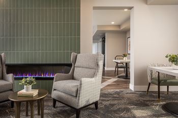A living room with a fireplace and a grey armchair.